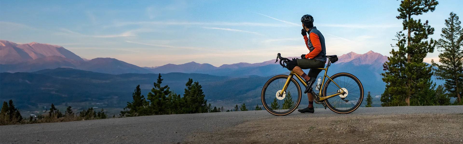 male cyclist stopped on his ride to take in the sunset over mountains